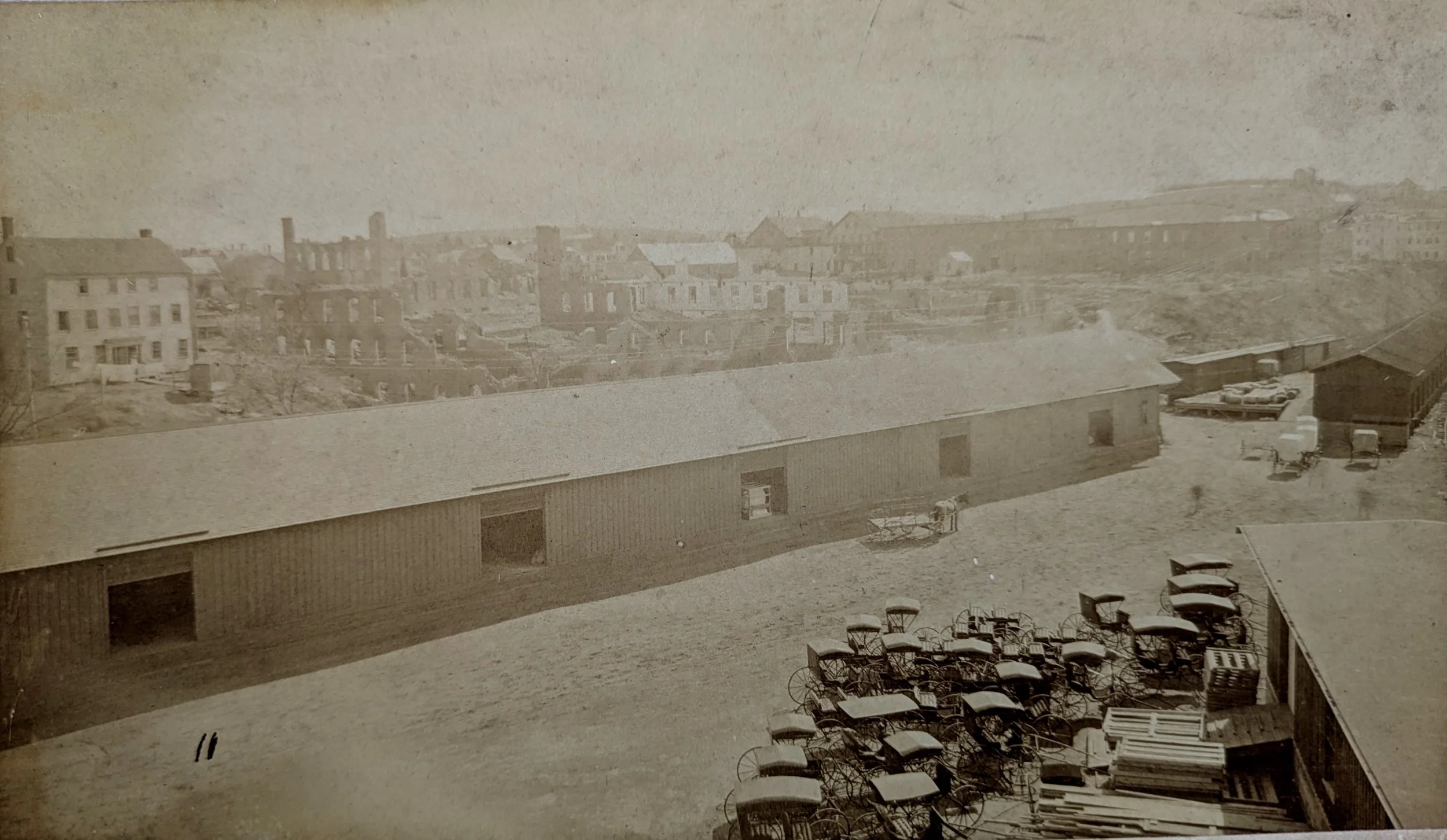 This very interesting photo shows carriages ready to be loaded on a "ghost train" in the foreground, with the ruins of multiple buildings in the background, so it would be some time after the 1888 Carriage Hill Fire.