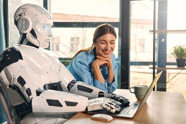 Assistente de IA ao lado de uma mulher sorrindo diante de um laptop, representando um agente de IA na saúde apoiando a equipe da clínica.