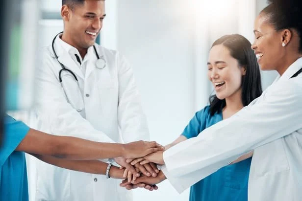 Equipe de saúde unindo as mãos, representando o time aliviado pela automação da pesquisa de CSAT