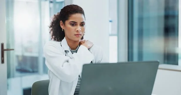 Médica com expressão preocupada analisando dados de no-show na clínica no notebook