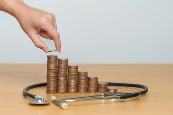 Moedas empilhadas em ordem crescente ao lado de estetoscópio ilustrando retorno sobre investimento em clínica
