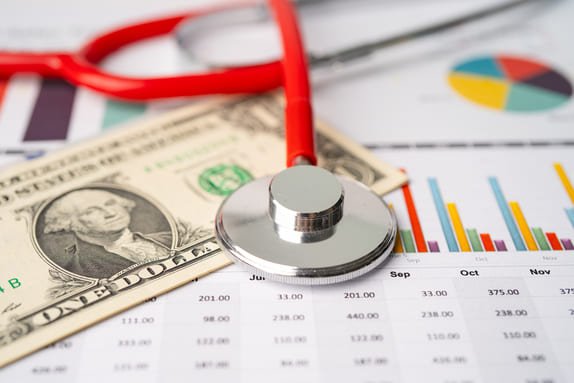 Estetoscópio sobre relatório com gráficos e dinheiro representando indicadores financeiros da clínica