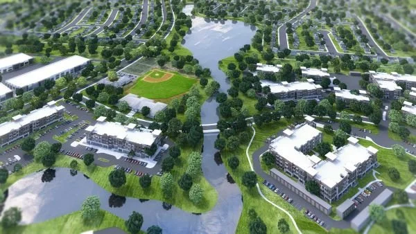 Aerial view of a planned residential community with housing, a baseball diamond, water features, and green spaces with trees and walkways.