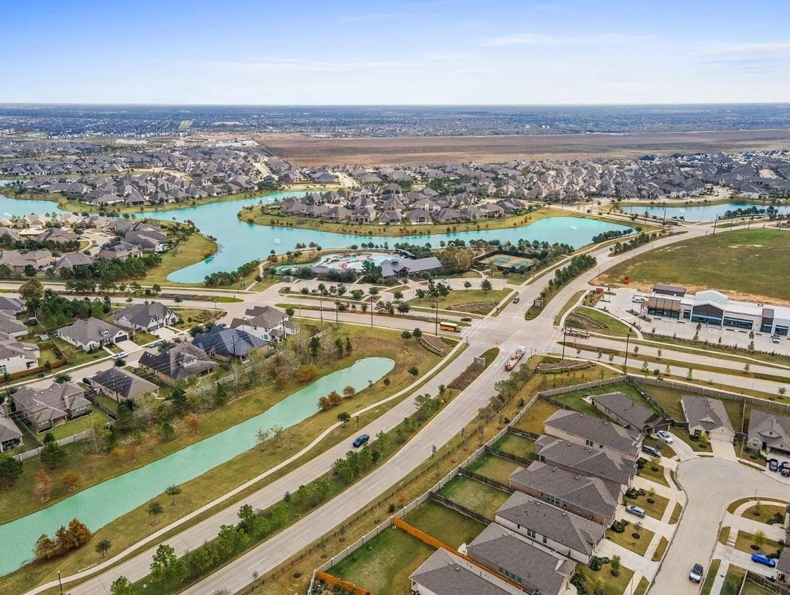 Aerial view of a suburban residential neighborhood with lakes, roads, and houses.