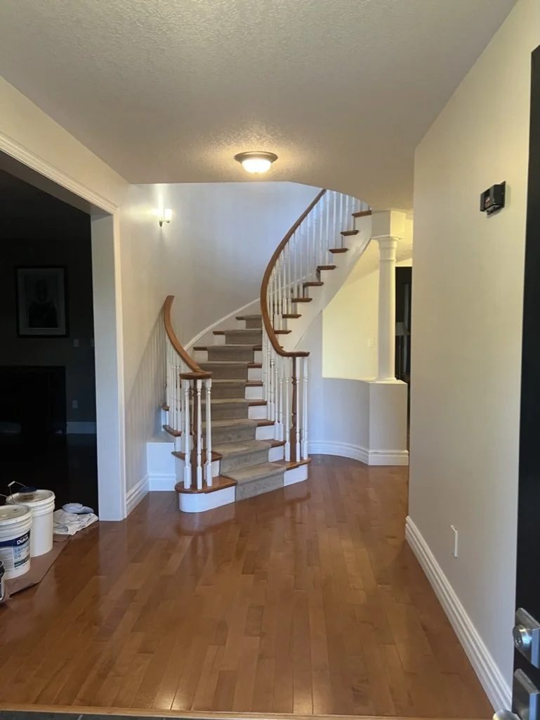 Interior of a house showing a curved staircase with white risers and wood handrails.