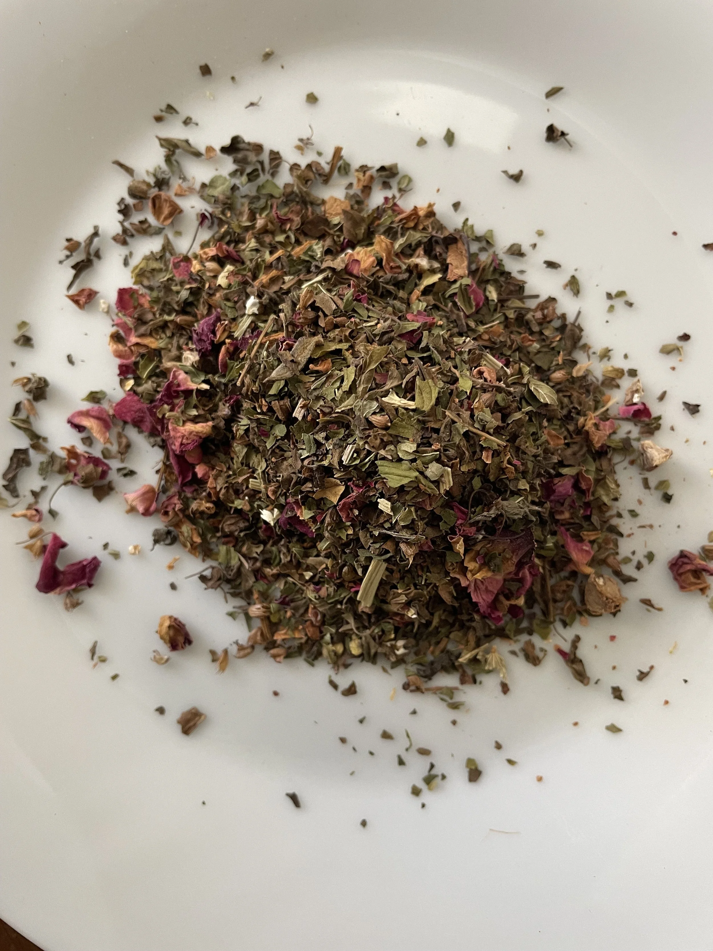 Loose leaf herbs including tulsi, peppermint, rose petals, cinnamon, gotu kola, and cardamom used in Byrde’s Balance herbal tea blend.