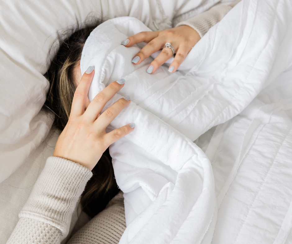 Woman with her head under the covers looking frustrated