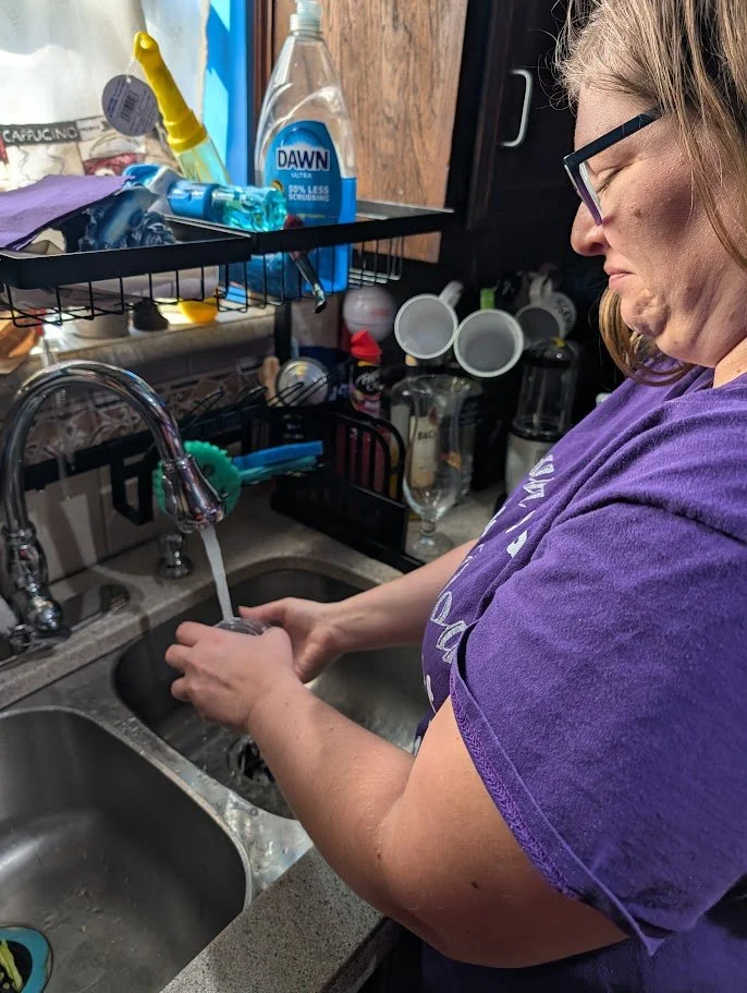 Postpartum Doula Melanie Powell washing dishes in a Mansfield families home.