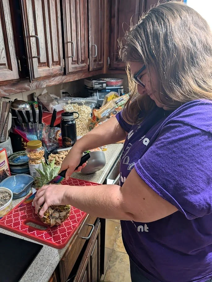 Doula Melanie Powell in a clients home slicing a pinapple for a snack for mom postpartum