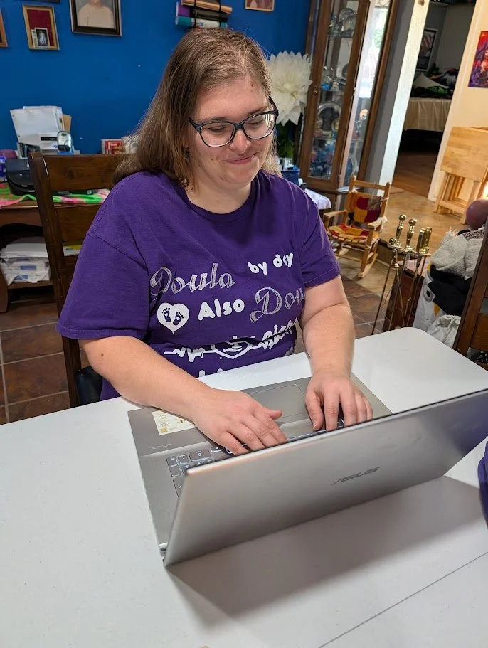 Christian Childbirth Educator Melanie Powell sitting at her laptop ready to teach an individual All-inclusive Bloom Class