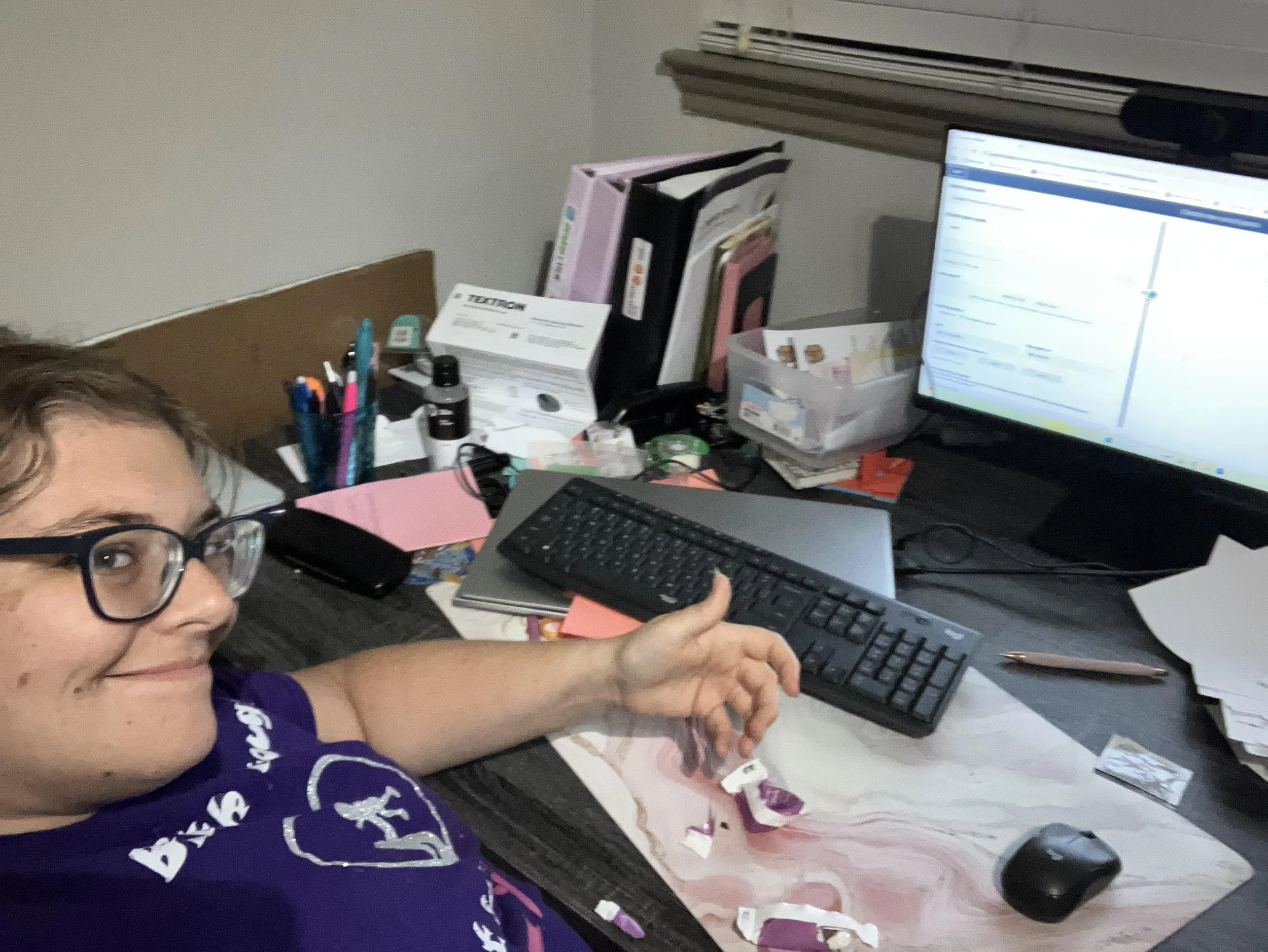 "Childbirth educator Melanie Powell sitting at her desk smiling as she prepares for an empowering, Christ-centered class."