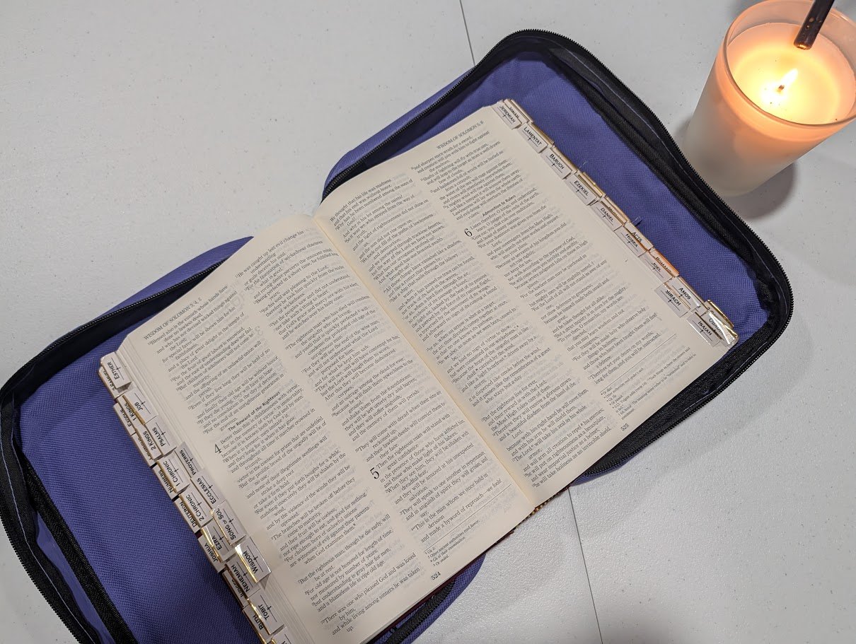 image of a bible opened up next to a lit candle