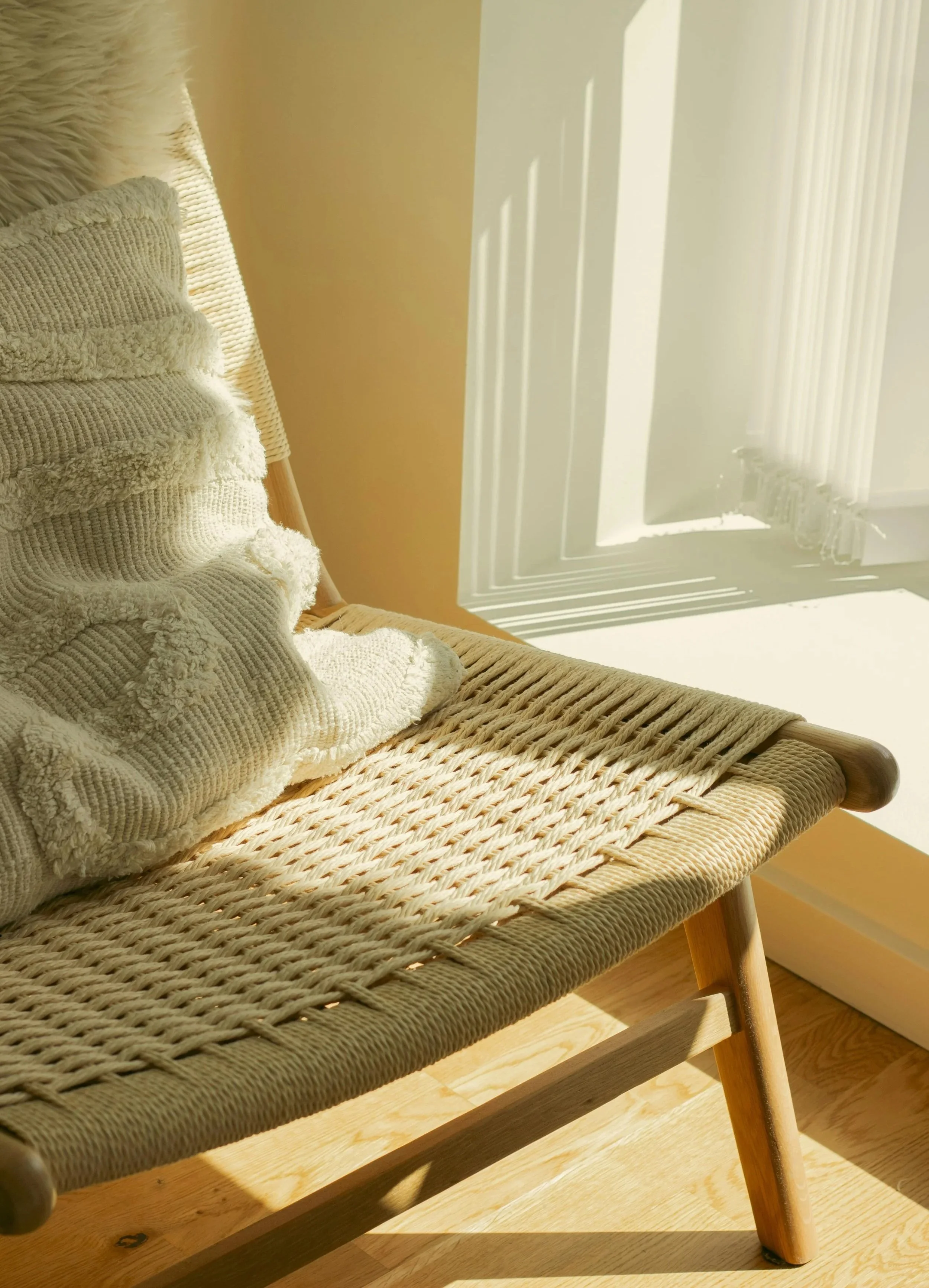 white chair with a white patterned pillow in a sunlit room with hardwood floors