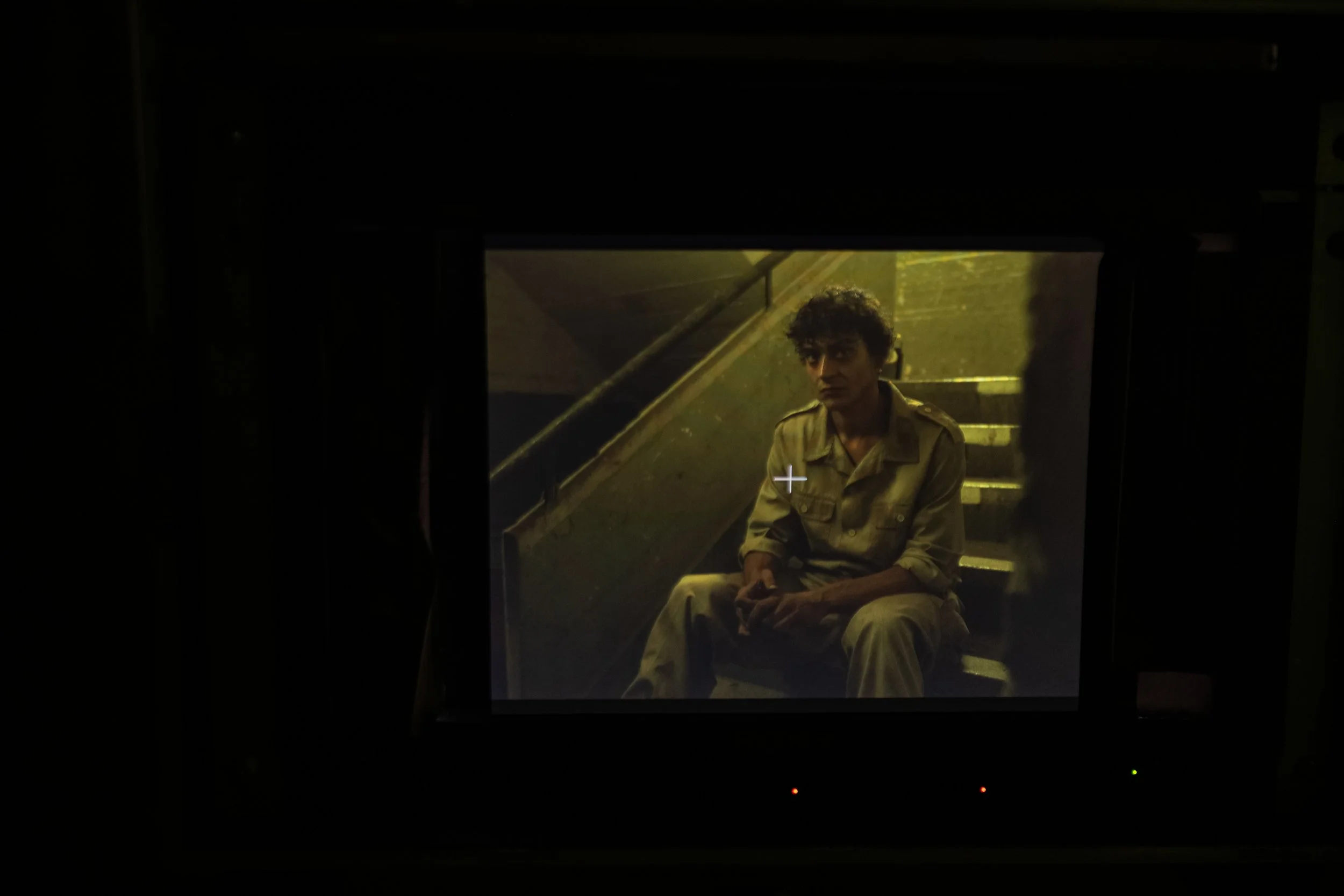 Ein junger Mann sitzt auf einer Treppe in einem dunklen Raum, beleuchtet von einem Bildschirm vor ihm.