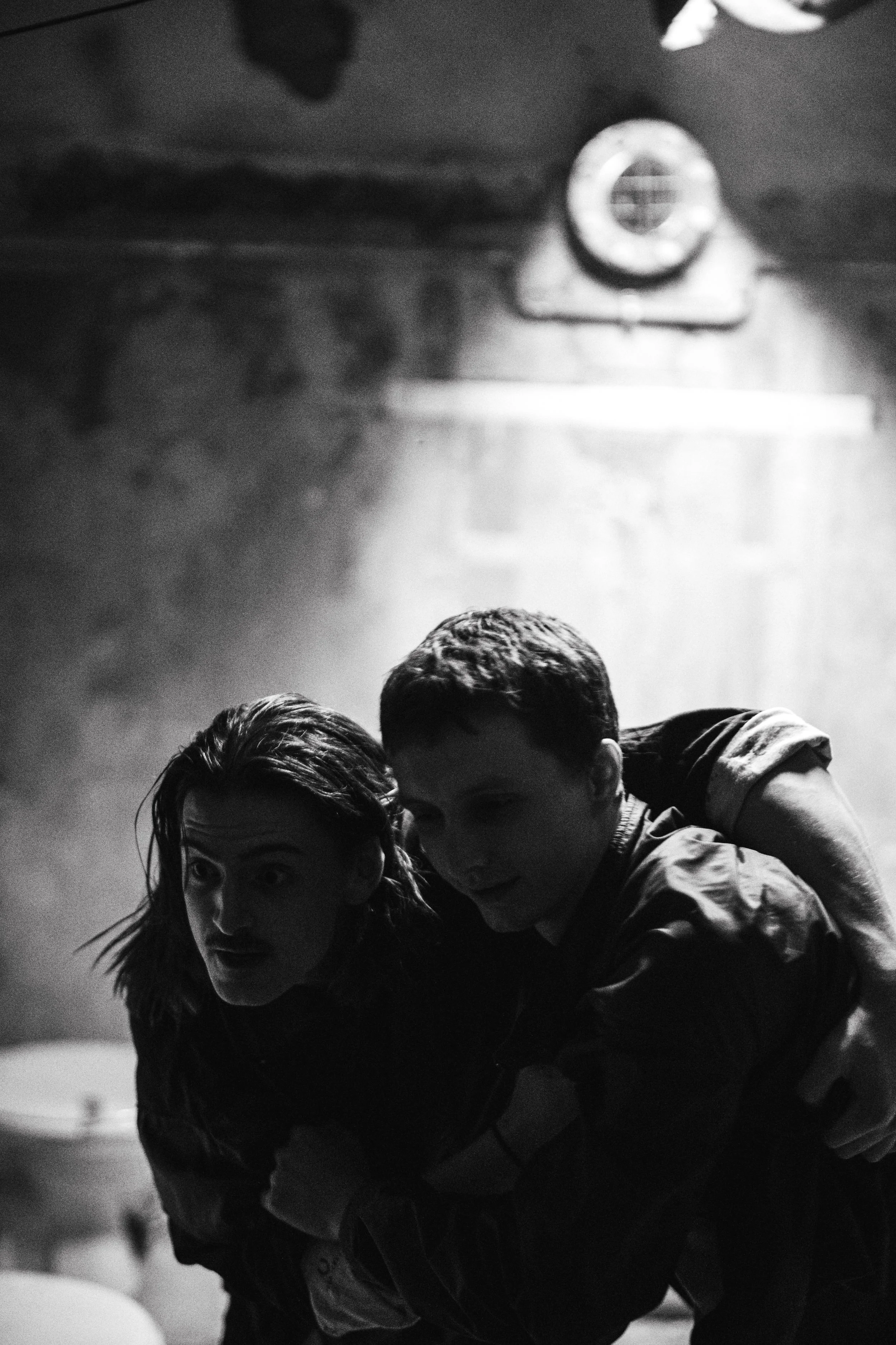 Zwei Menschen beim Kampf im Schwitzkasten in einem dunklen Raum, schwarz-weiße Aufnahme.