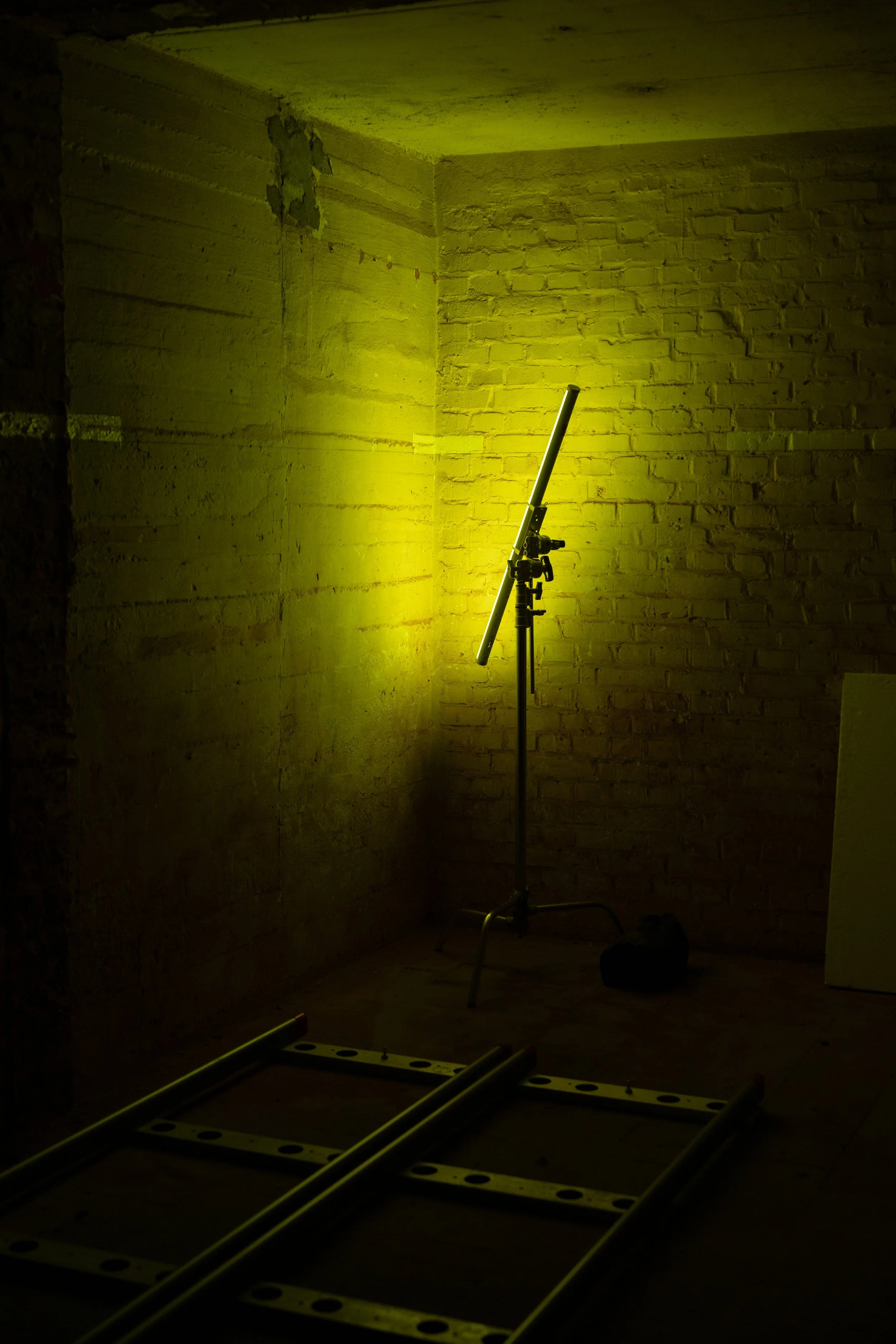 Ein Baustudio mit einem Scheinwerfer auf einem Stativ, einer Leiter auf dem Boden und einer unvollendeten Innenwand mit Ziegeln.