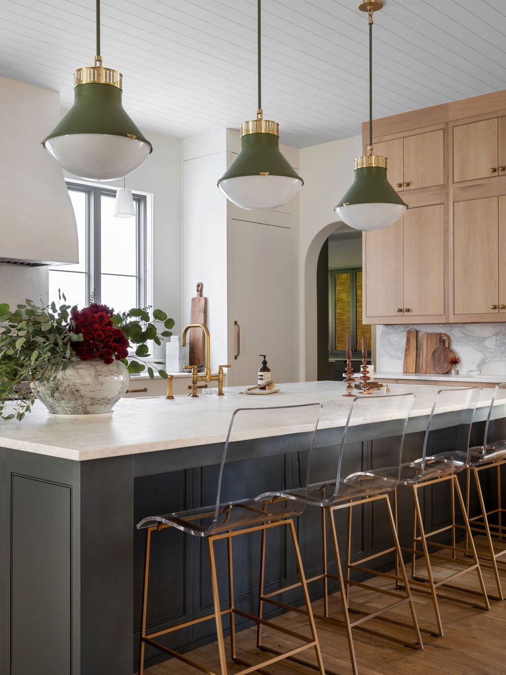 Modern kitchen with a white marble island, pendant lights, and wooden cabinets.