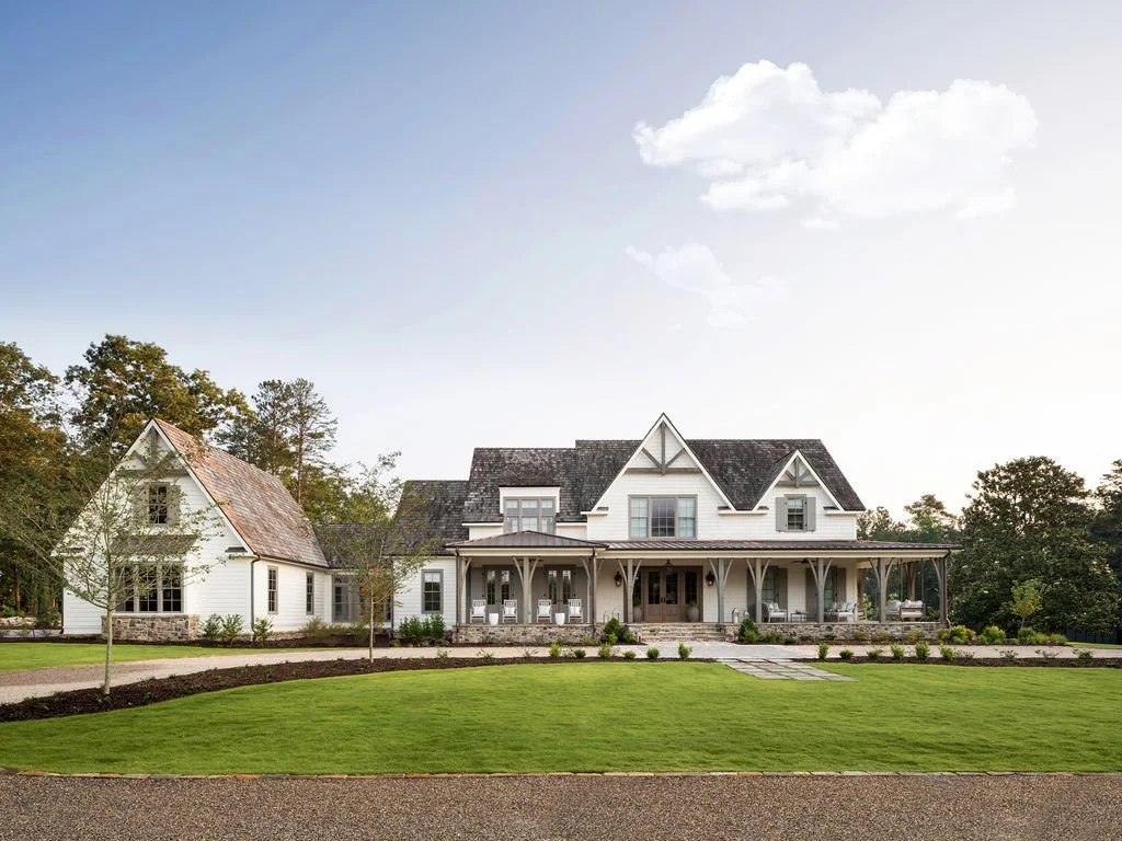 Large white house with multiple gables, covered porch, and a landscaped front yard.