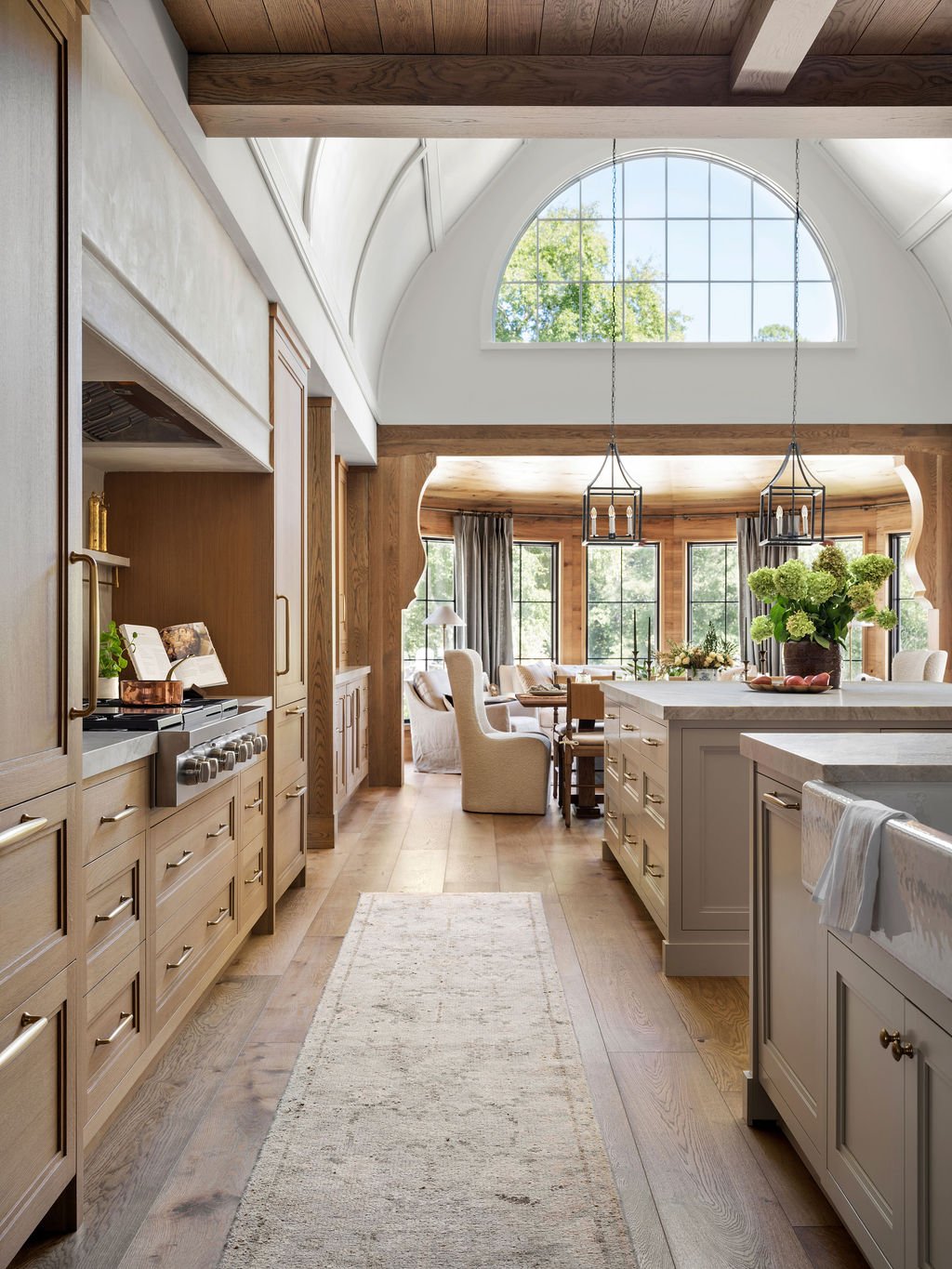 Bright open-concept kitchen and living room with large arched window, wooden accents, and modern decor.