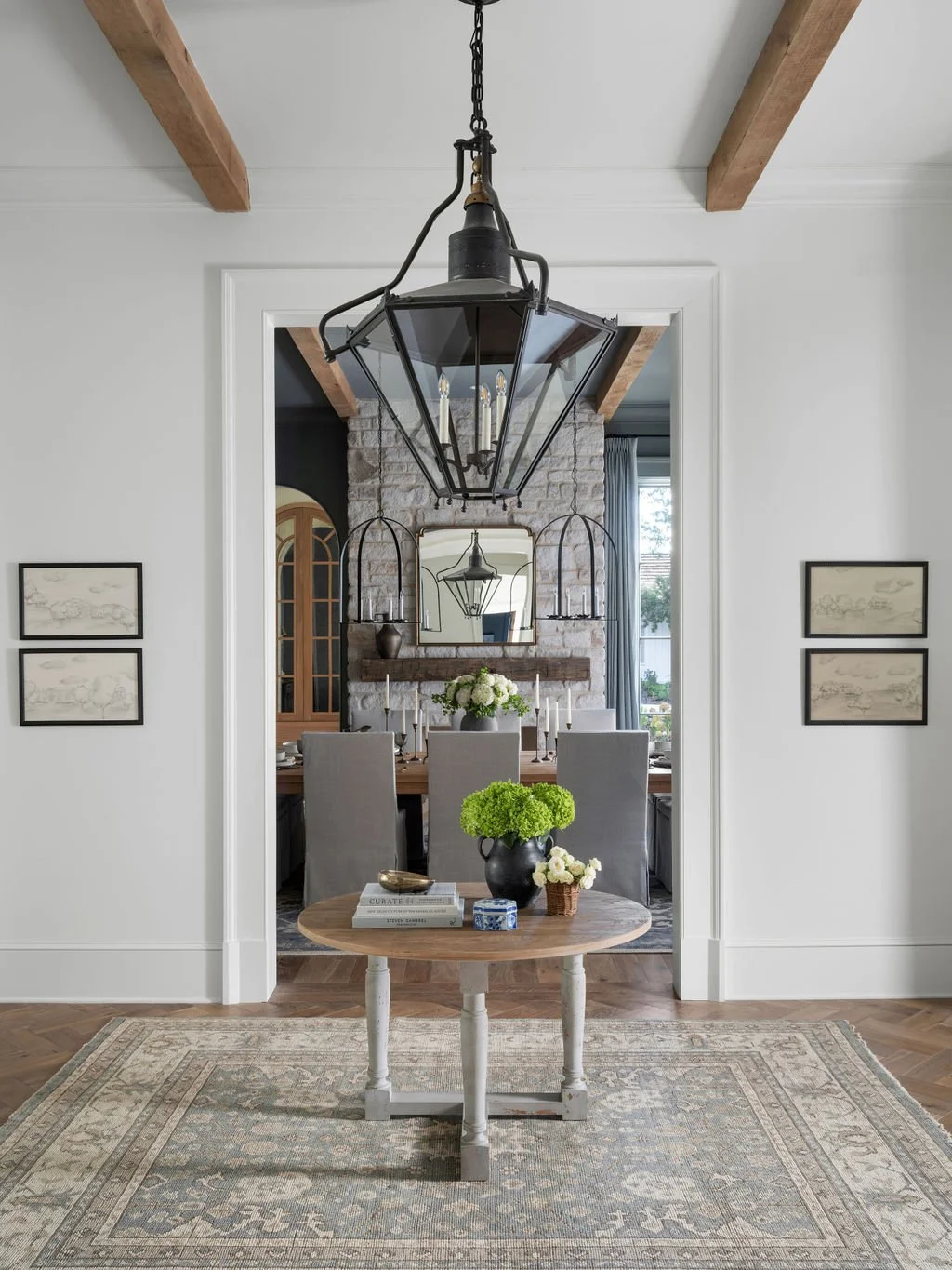 Dining room with a chandelier, a brick fireplace, a mirror, and a table set with candles and flowers.