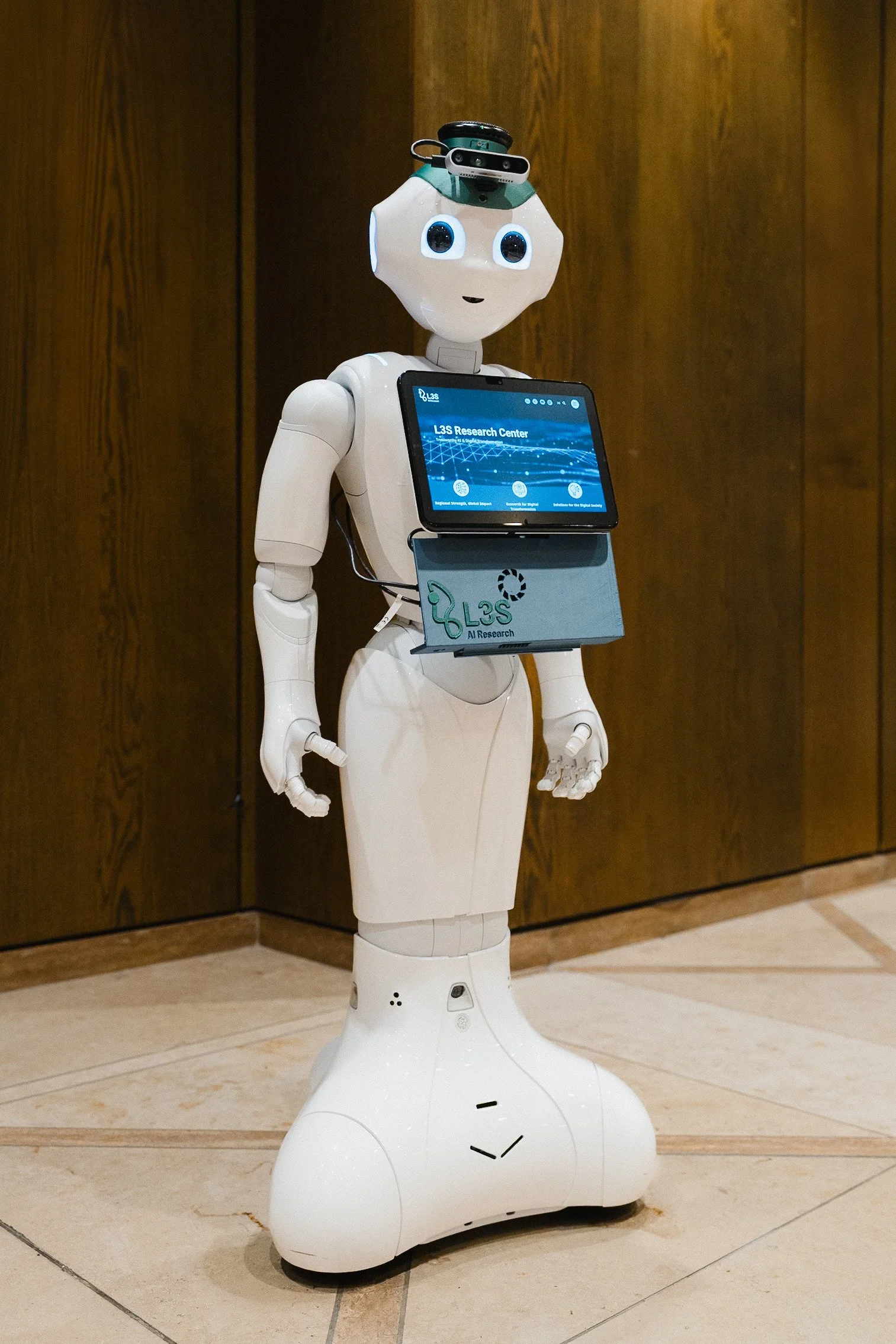 Ein humanoider Roboter mit einem Tablet an der Brust in einer Innenumgebung mit Holzvertäfelung.