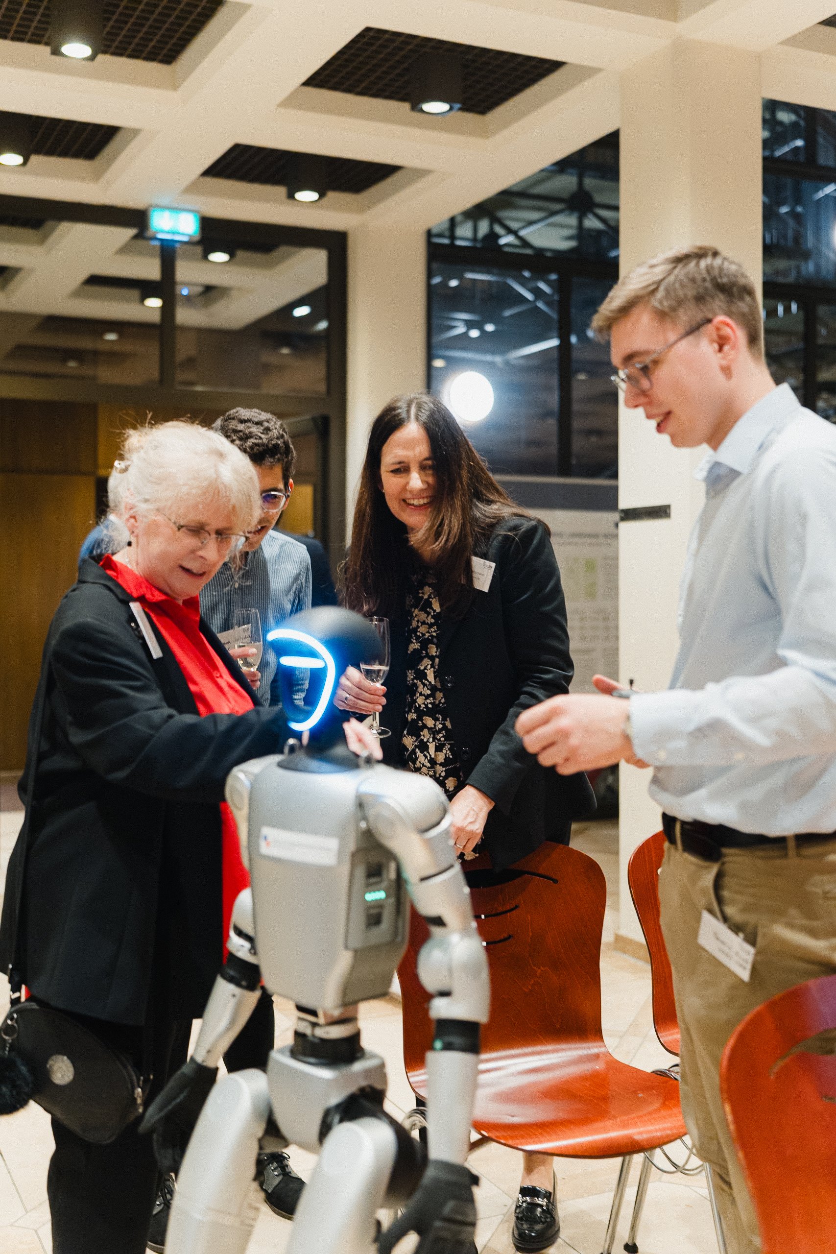 Menschen unterhalten sich mit einem Roboter in einem modern gestalteten Raum.
