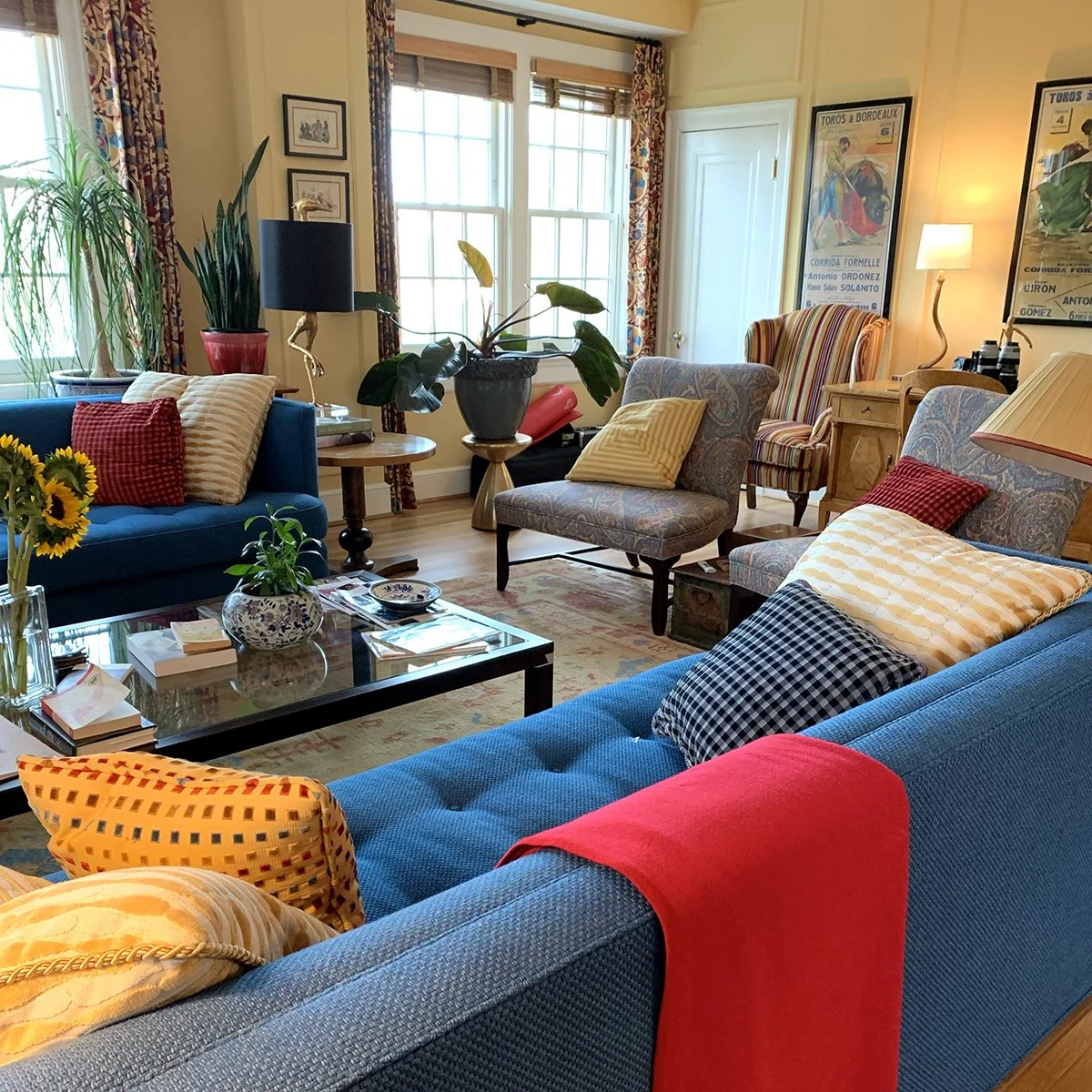 living room with blue couch, yellow walls and vintage prints