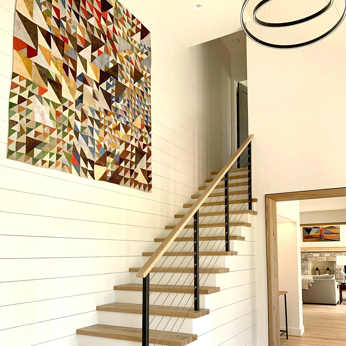 white clapboard stairway with quilt wall hanging