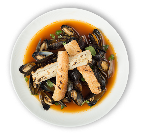 A bowl of mussels in broth garnished with chopped herbs and toasted bread strips