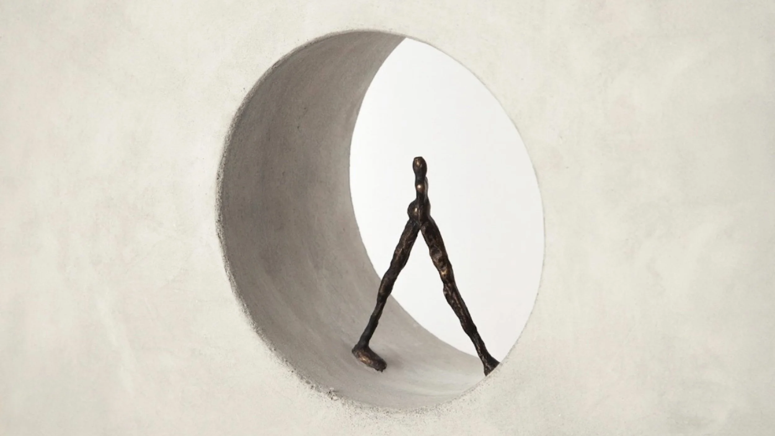 A small, abstract human-like sculpture walking through a circular tunnel in a minimalistic white space.