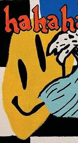 Part of a cartoon-style illustration with the word "hahaha" in red and black letters, a large yellow smiling face, and a character with white hair, glasses, and a blue shirt.