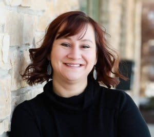 Headshot of a business woman against a brick wall outside