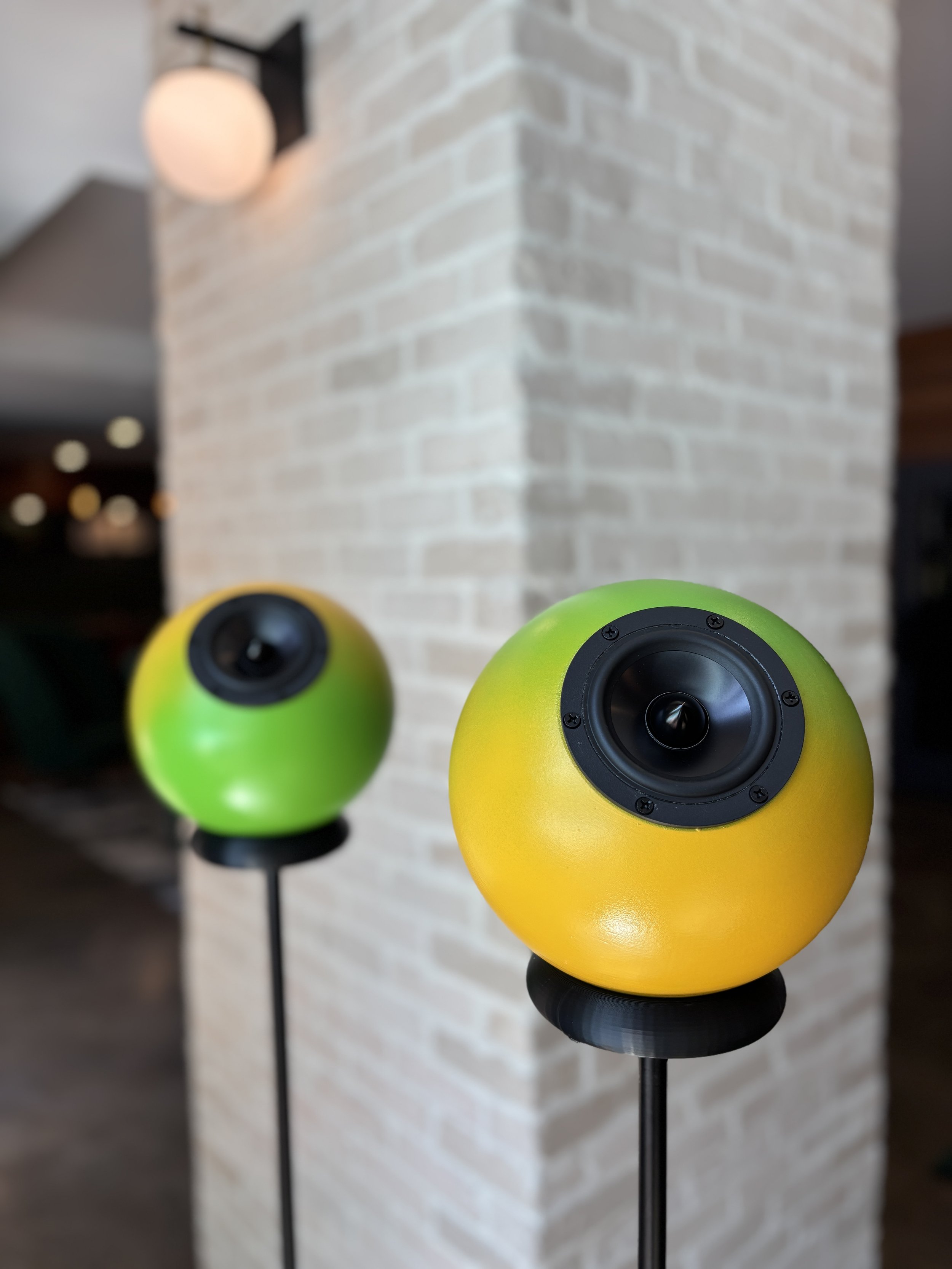 Close-up of colorful spherical speakers with a brick wall background.