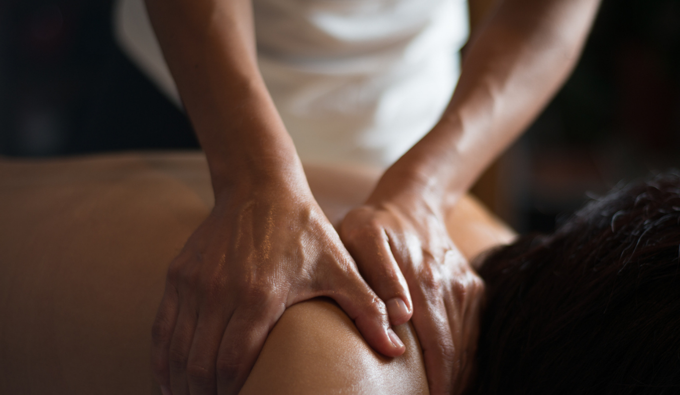 Person receiving a massage, focusing on their back being massaged by a therapist.