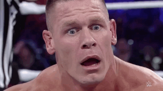 Close-up of a male wrestler with a shocked expression in a wrestling ring.