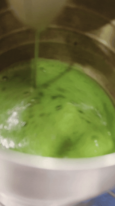 A close-up view of green liquid being poured into a container.