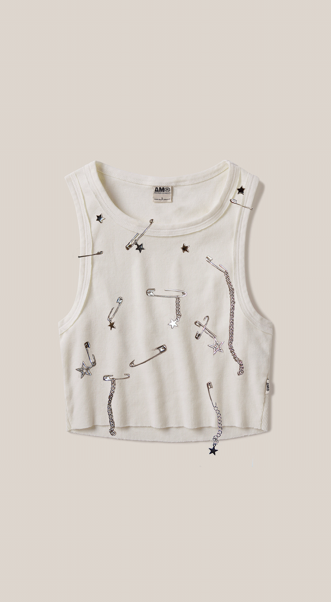 White sleeveless top with star-patterned safety pins and chains
