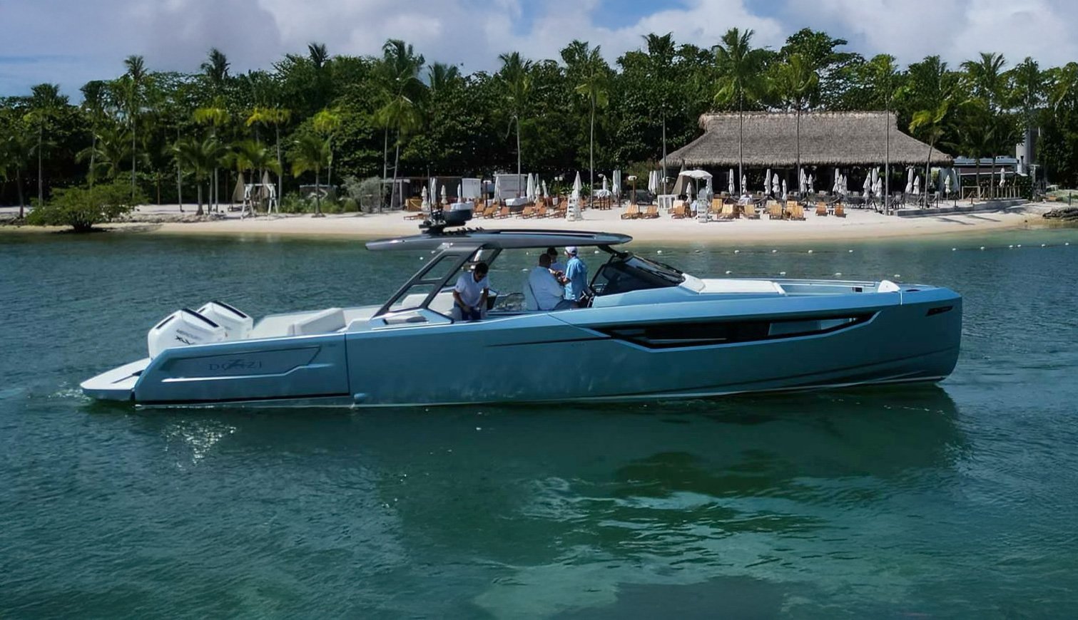 A modern luxury yacht sailing near a tropical beach with palm trees and a thatched-roof resort in the background.