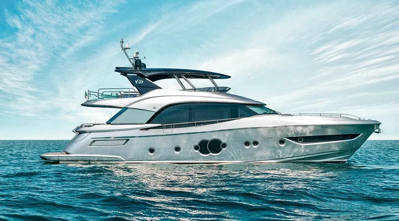 A large modern yacht sailing in the ocean with a partly cloudy sky in the background.