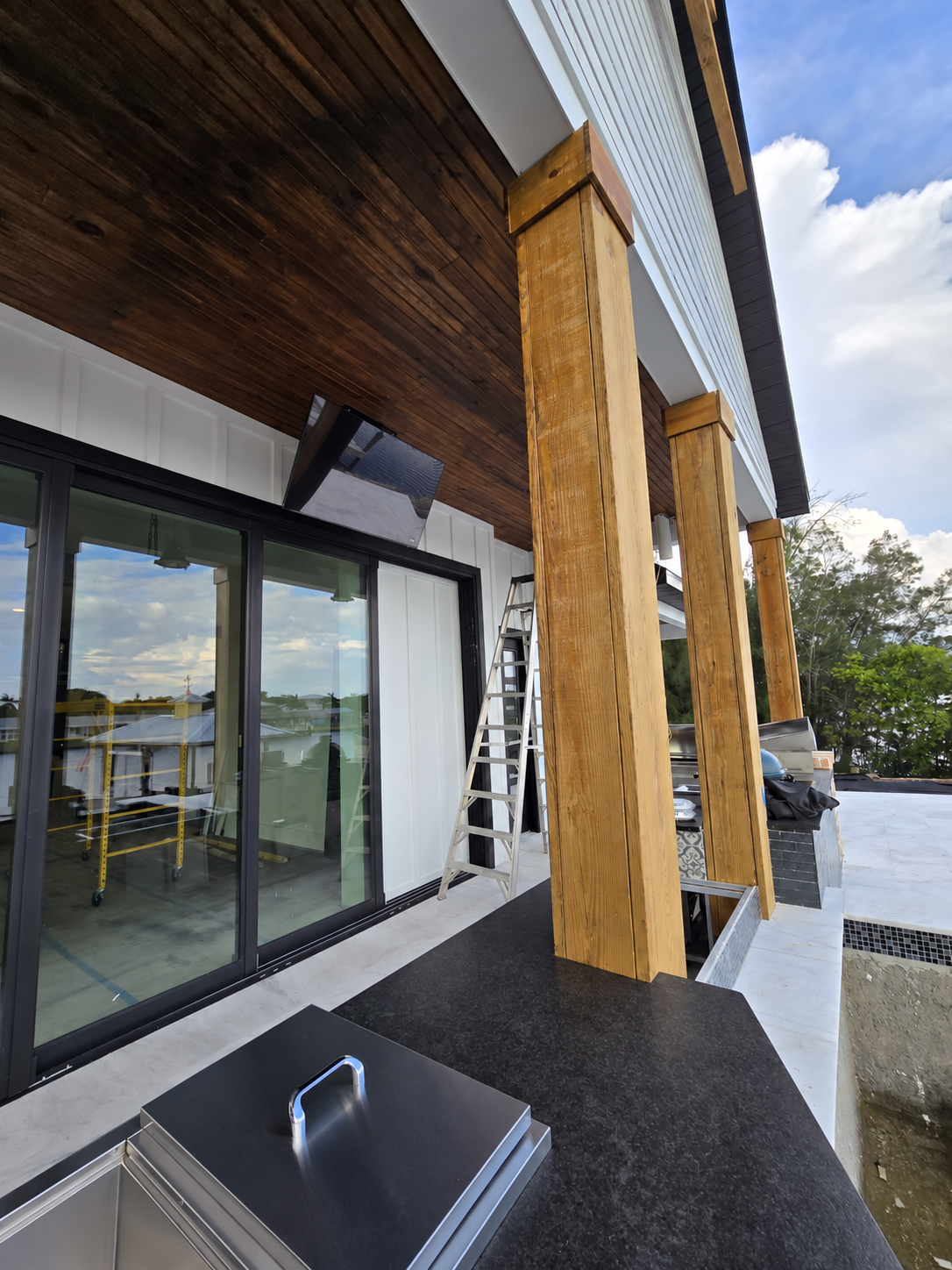Poolside TV installed on a motorized mount above sliding doors for adjustable outdoor viewing in Ruskin, Florida.