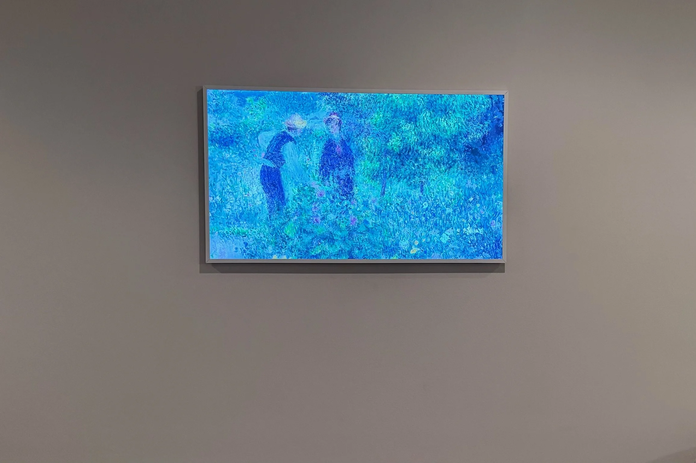 Digital artwork on a wall showing two people standing outdoors among greenery, with dots of vibrant colors creating an abstract effect.