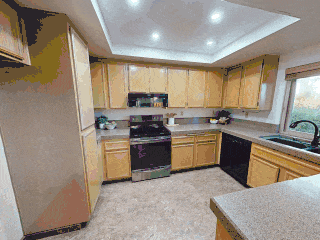 Kitchen with wooden cabinets, black appliances, a window over the sink, and a beige countertop.