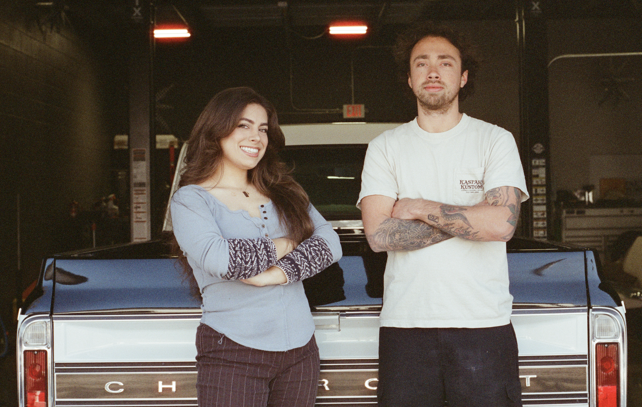 Husband and wife owners take a photo in front of a black and white chevy classic truck