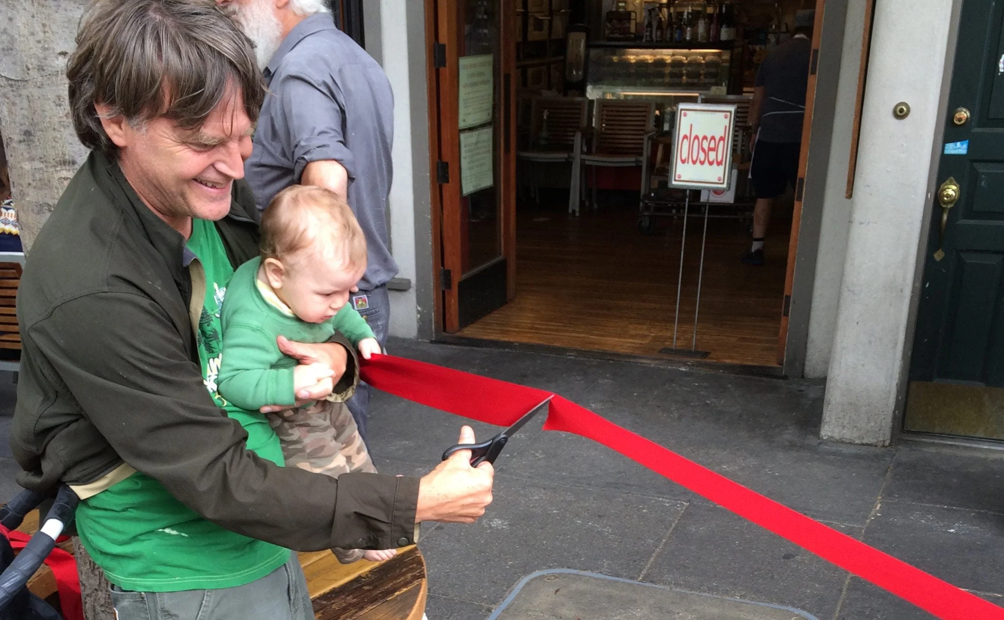 Public ribbon-cutting event at the newly completed parklet, people seated and mingling in the sidewalk space