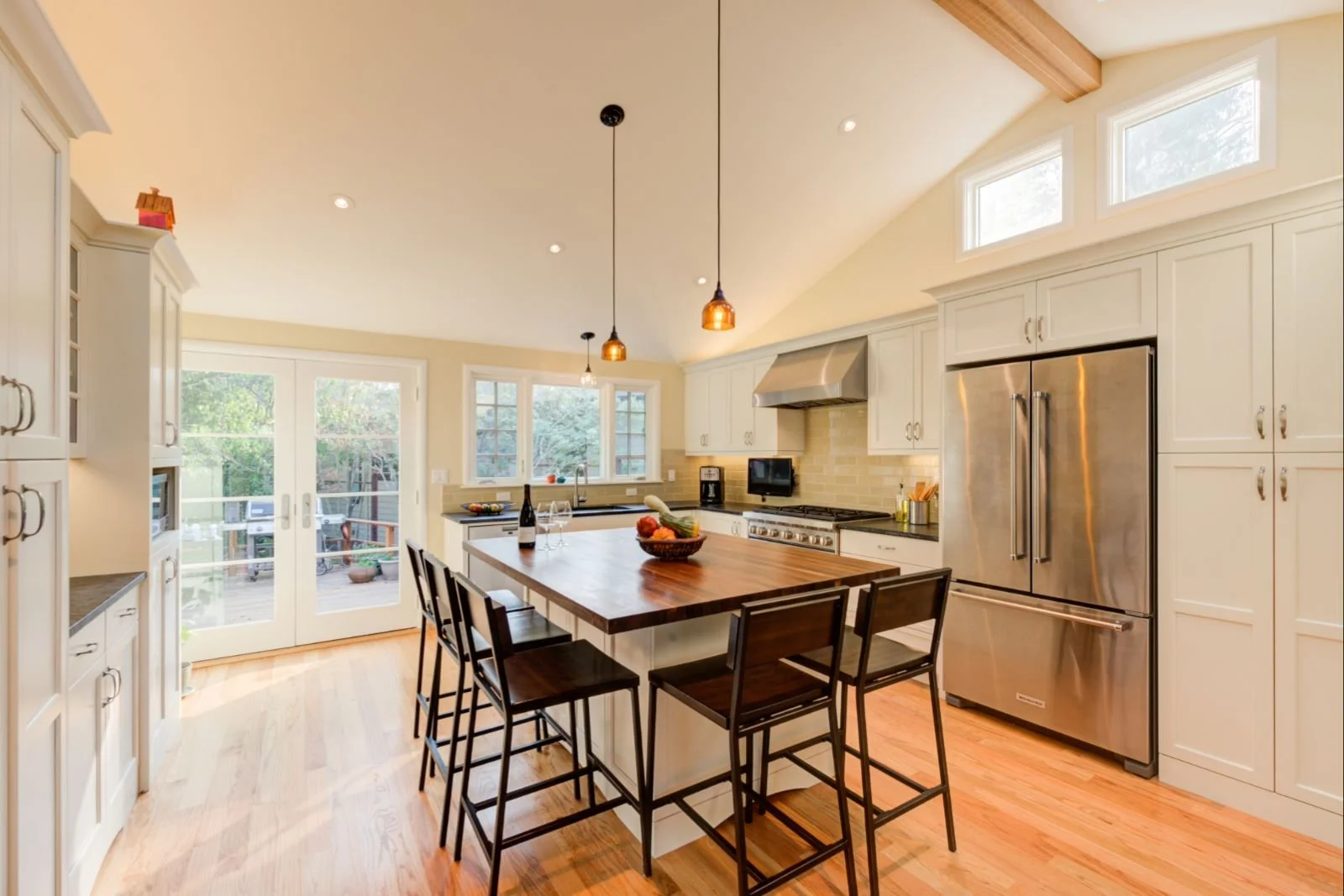 New Kitchen with large island, vaulted ceilings and new skylights looking toward new deck 