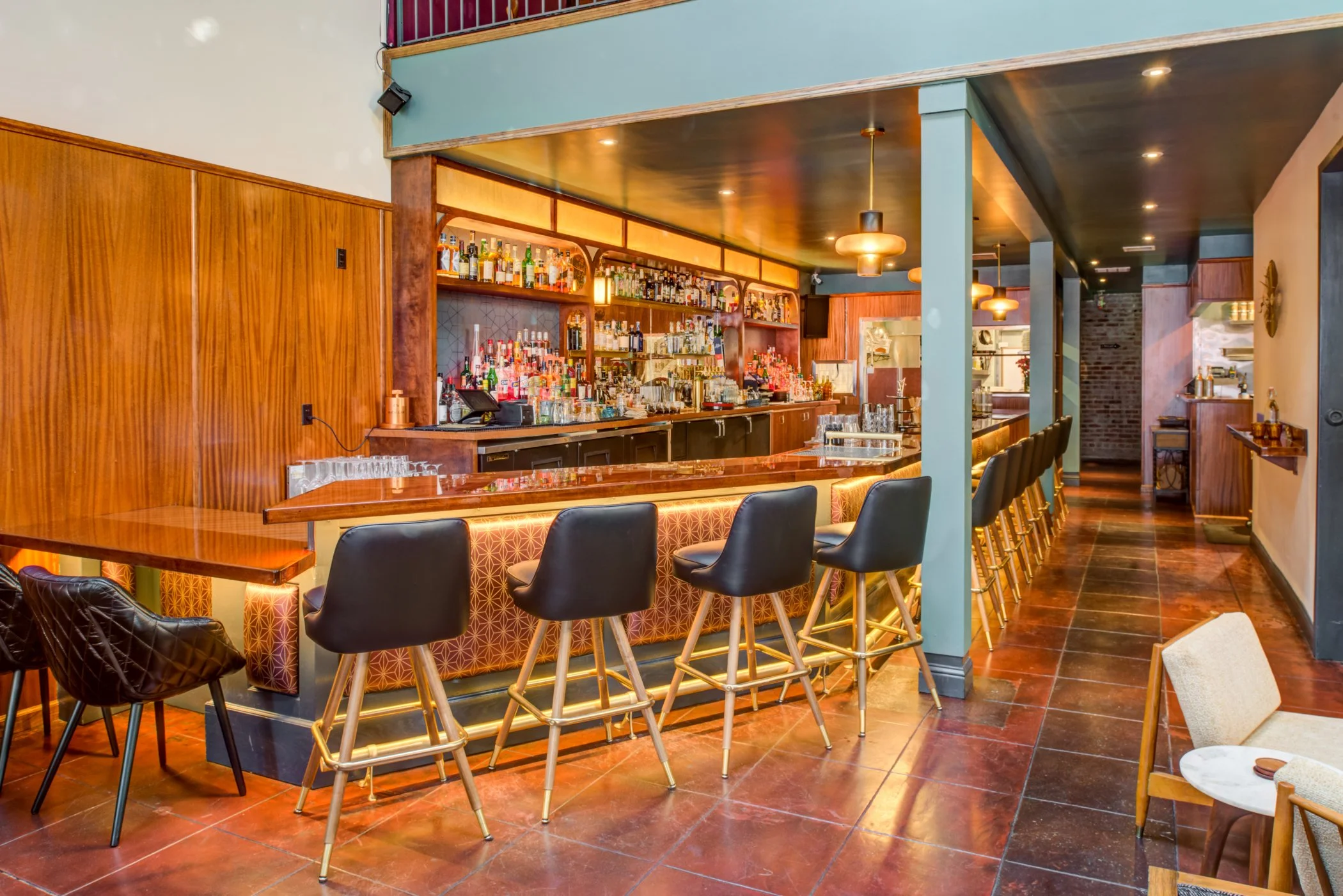 Bardo Lounge bar with brass foot rail, leather stools, and illuminated geometric paneling.