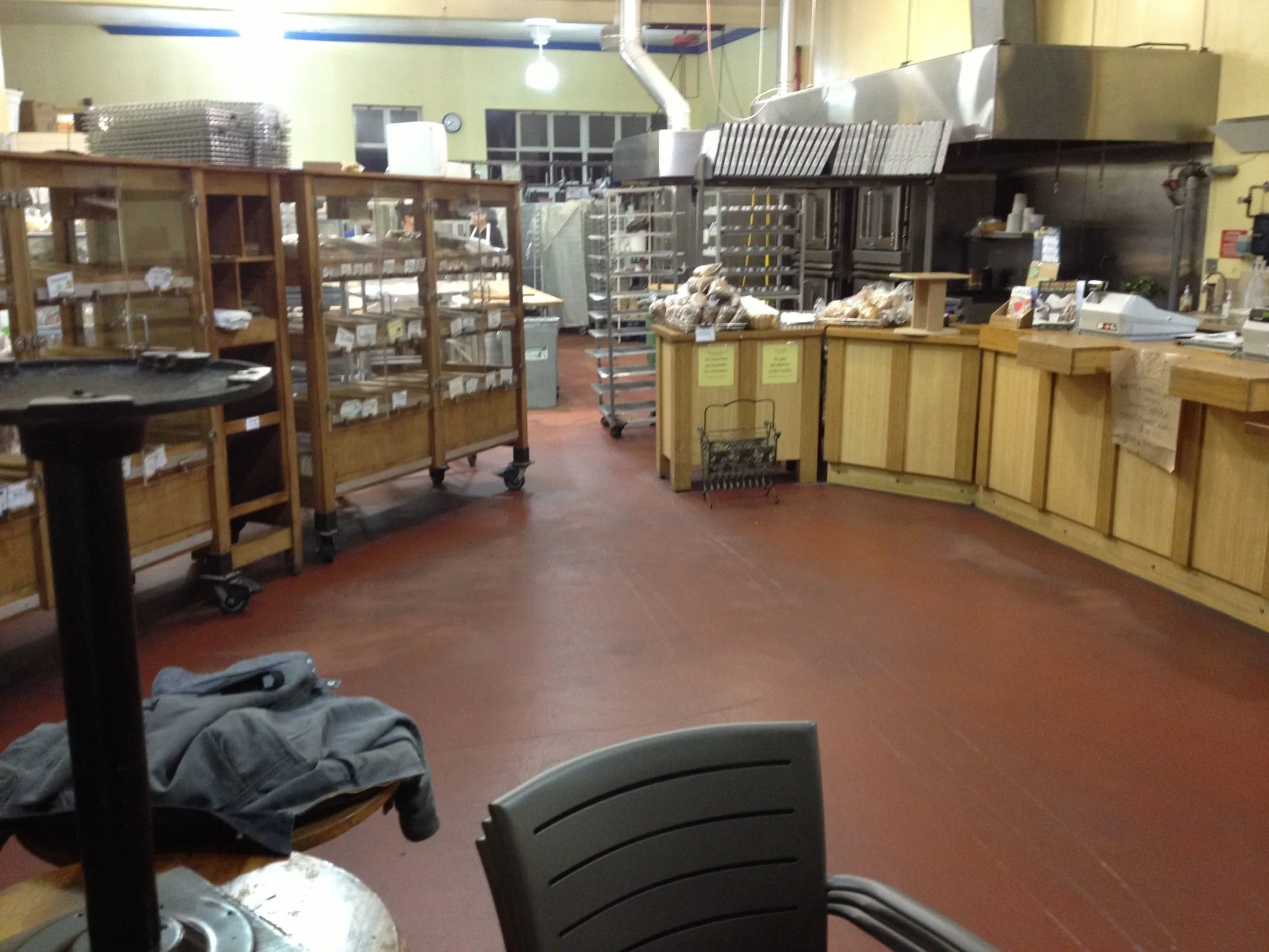 Interior of Arizmendi Bakery showing the finished production floor with wood display cases, service counters, and commercial baking equipment arranged for efficient workflow and customer visibility.