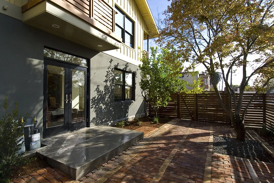 Private outdoor patio with recycled brick paving, wood fencing, and seating area that supports indoor outdoor living while maintaining privacy and a low maintenance landscape design.
