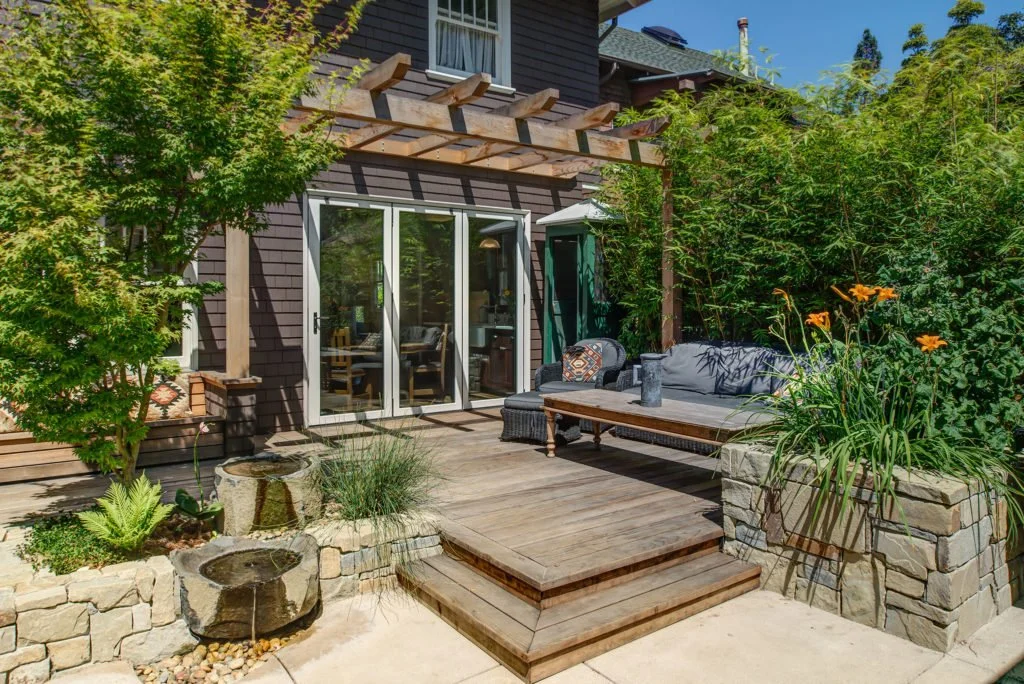 Exterior view of the redwood deck with the folding door wall closed, showing how the new doors frame the kitchen and connect the house to the patio year-round.