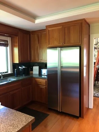 Existing kitchen before renovation, showing dark wood cabinets, older appliances, and limited natural light prior to the updated layout and finishes.